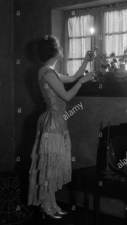 1920s-woman-party-dress-ruffles-on-skirt-placing-a-lighted-candle-AAM2CY